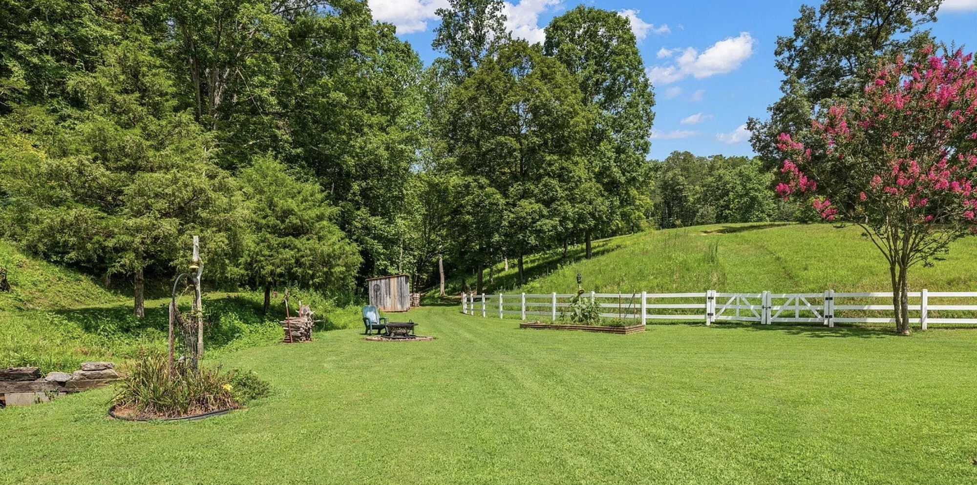 Rustic barn with red roof and star ornament, white fencing, pasture and creek