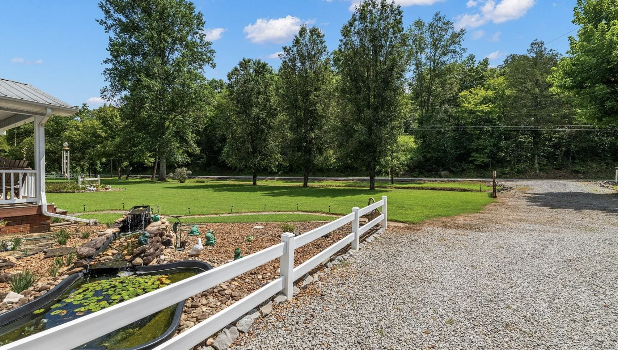 Lawn area with fire pit, Adirondack chair, white fencing, and blooming crape myrtle tree